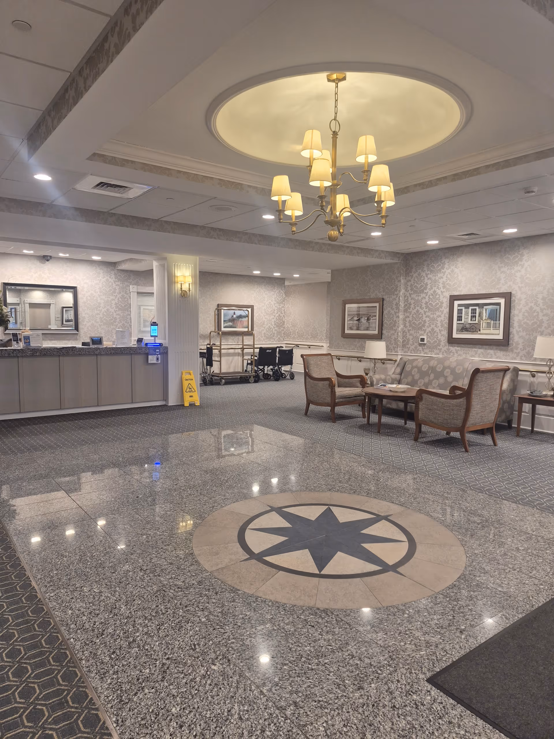 Spacious interior lobby with chandelier, reception desk, and seating area in a senior facility.