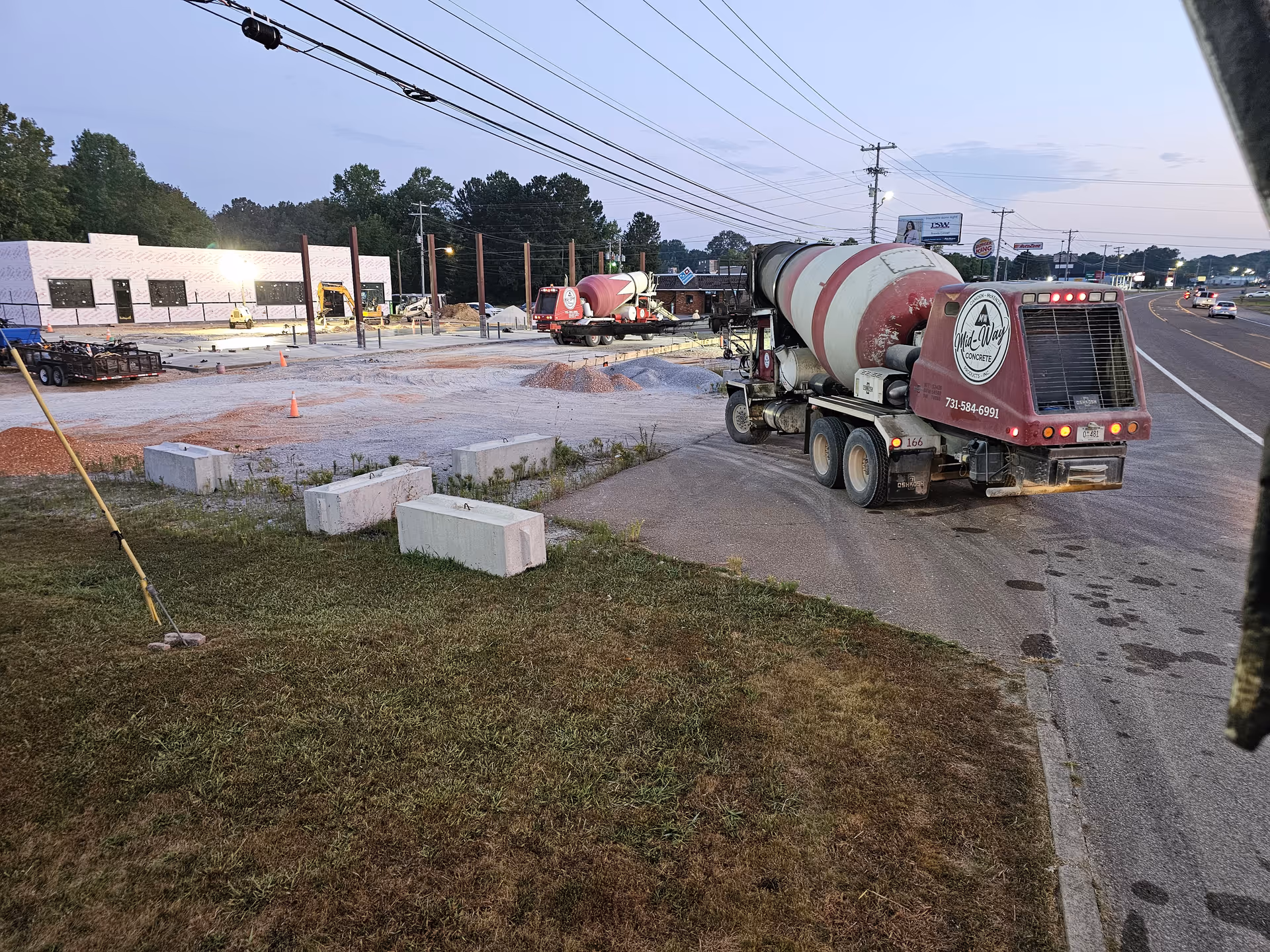 Construction site on a road with a concrete mixer truck and building under development.