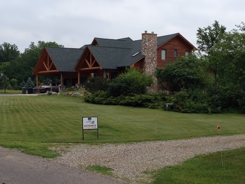ShadowTree Lodge exterior: a wooden lodge-style building with stone chimney, green lawn, and entrance sign.