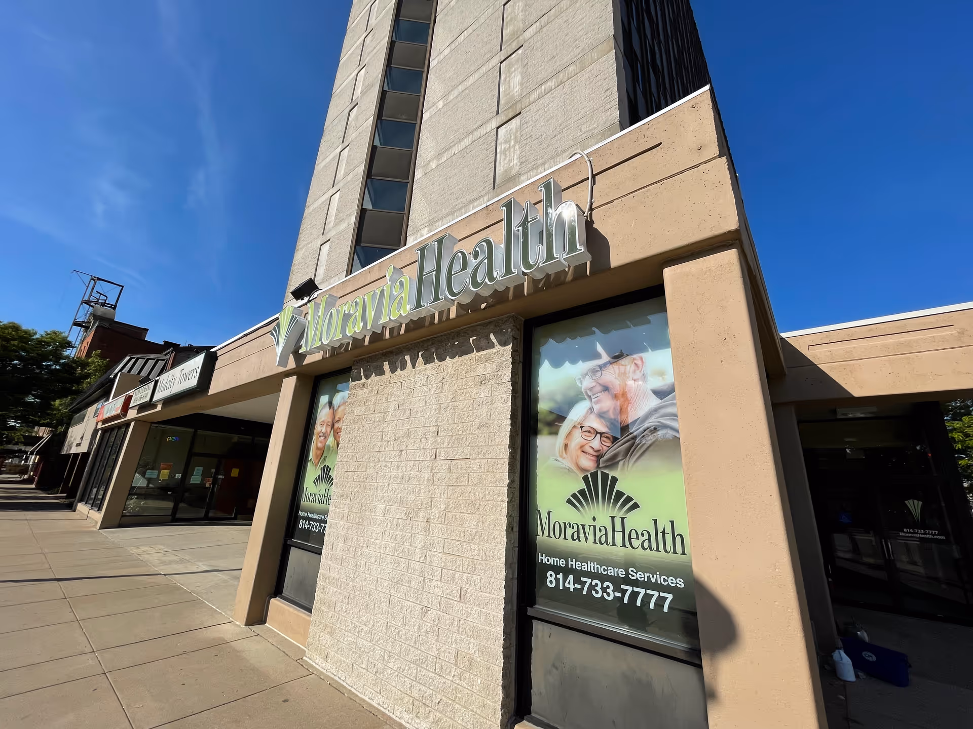 Exterior view of Moravia Health Erie facility with large sign and windows along sidewalk