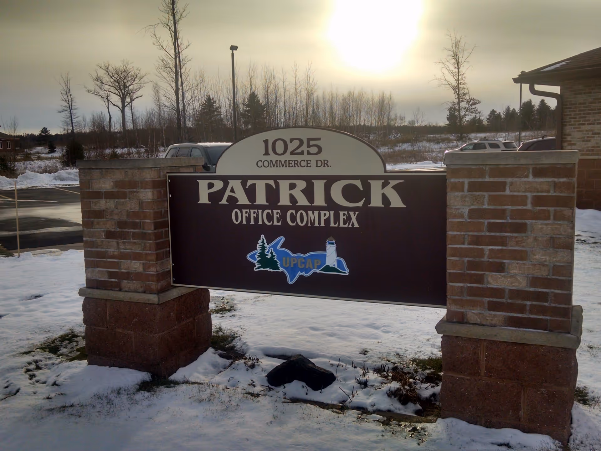 Outdoor entrance sign for Patrick Office Complex with UPCAP logo and brick pillars.