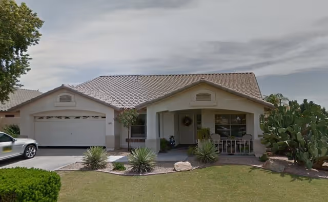 Front view of a single-story care home with a two-car garage and desert landscaping.