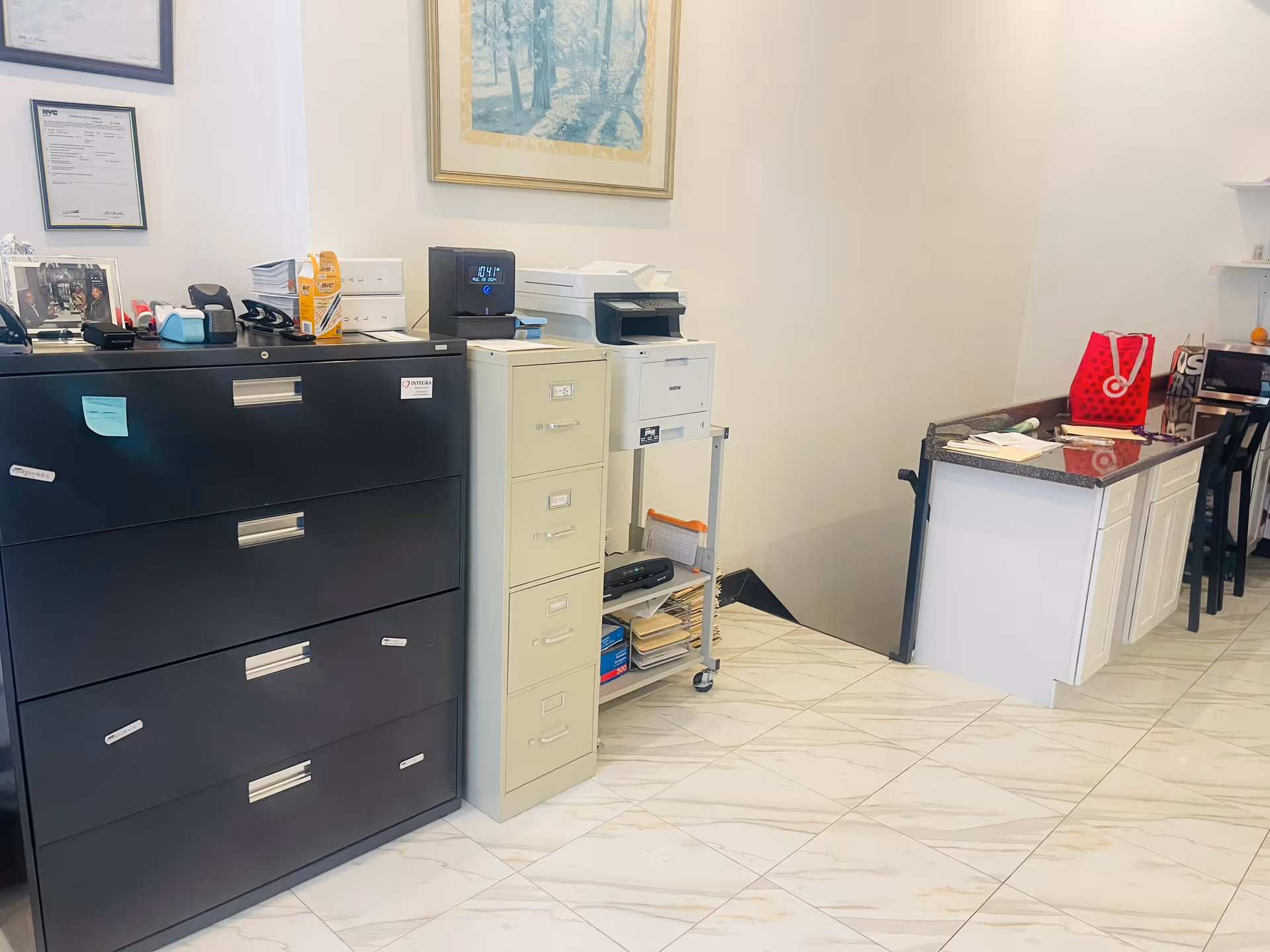 Reception area with filing cabinets, printer, and granite-topped counter in a clean well-lit facility.