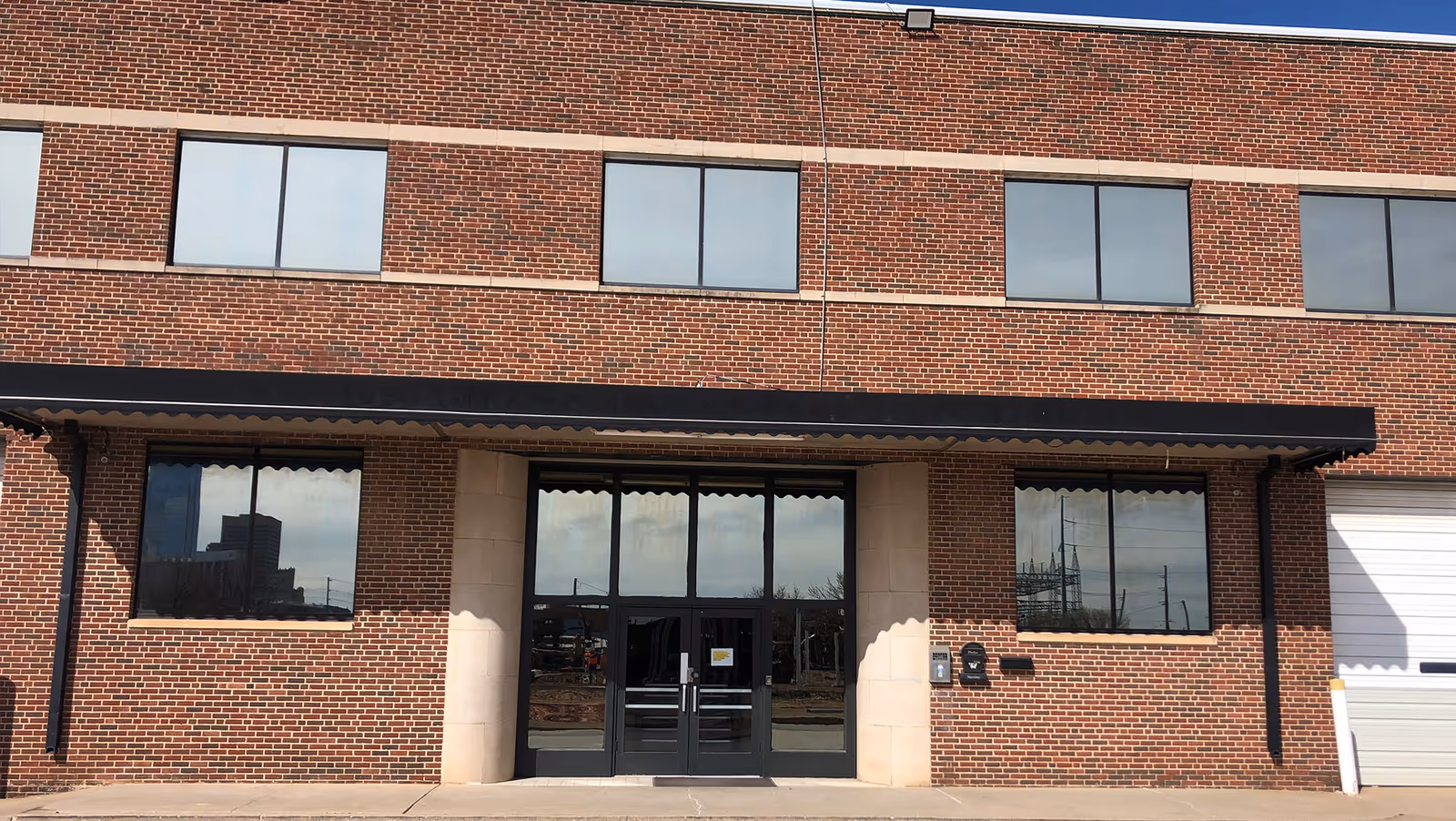 Red brick senior living facility front entrance with glass doors and large windows