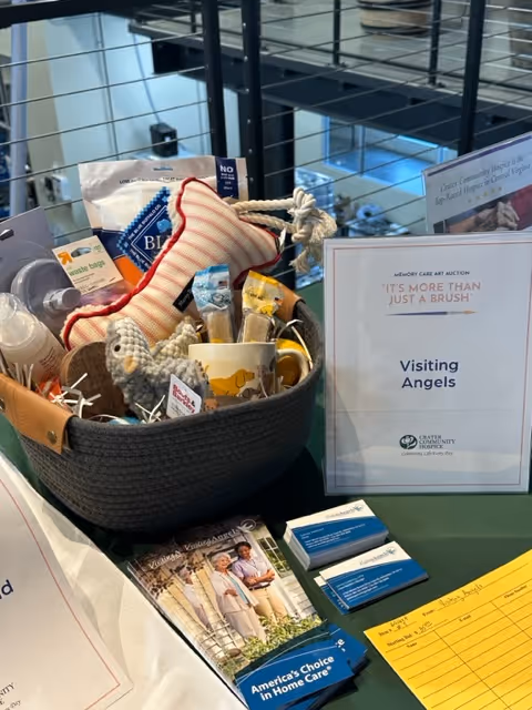 Basket of assorted items and brochures for Visiting Angels displayed on a display table.