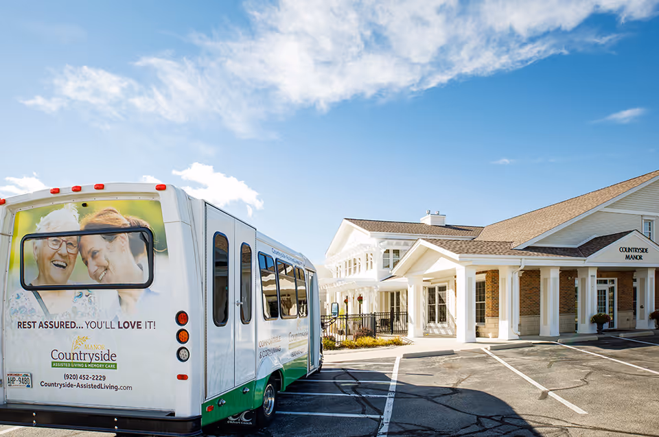 Exterior view of Countryside Manor senior living with a shuttle bus parked in front.
