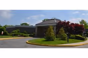 Exterior view of Carillon Nursing and Rehabilitation Center with curved driveway and landscaped entrance.