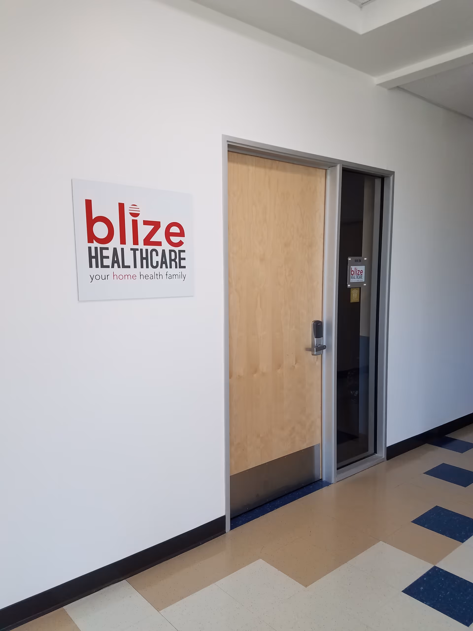 White hallway with a Blize Healthcare sign and a wooden door in a medical building
