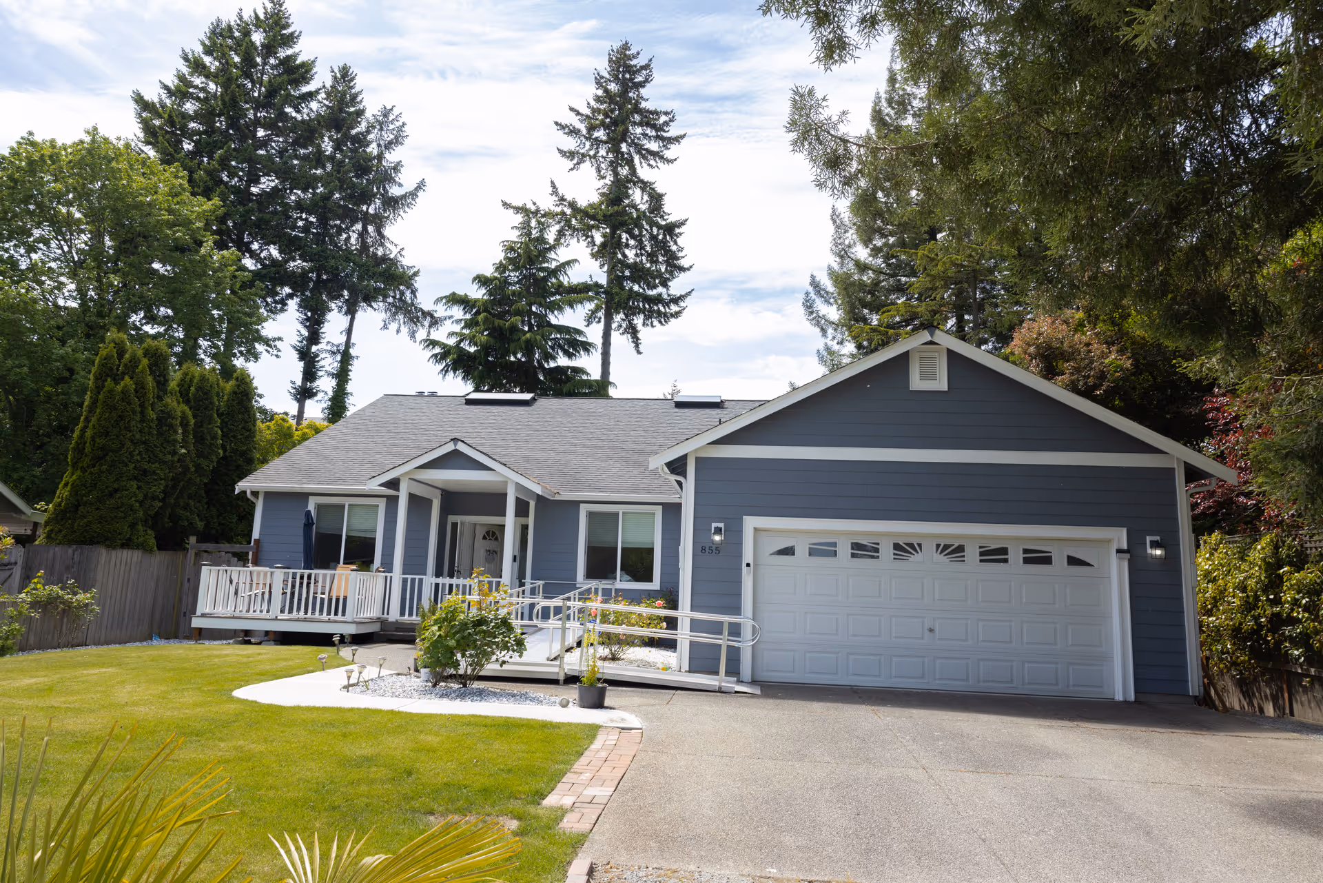 Blue single-story house with a front porch, ramp, and attached two-car garage.