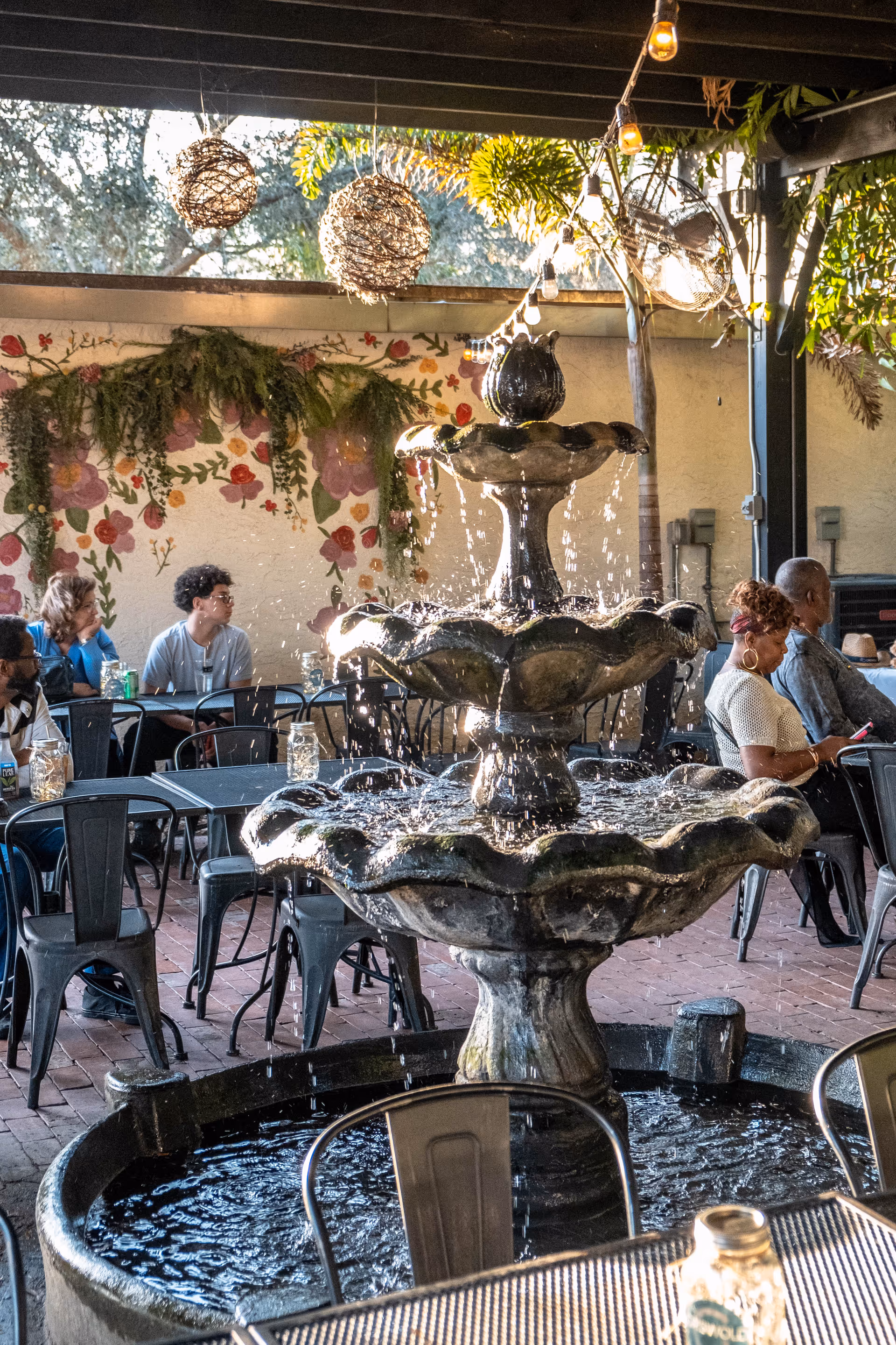 Outdoor patio featuring a tiered fountain, string lights, and residents seated at tables.