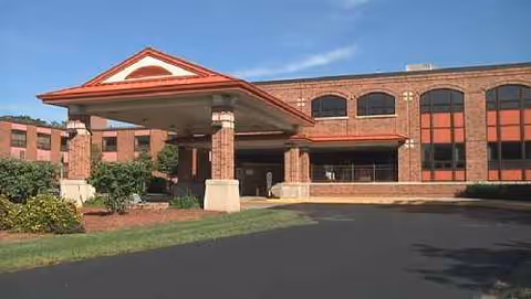 Brick nursing center exterior with porte-cochere entrance and arched windows.