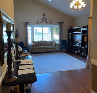 Cozy living room in a senior living facility with sofa, TV, rug, and wall decor.