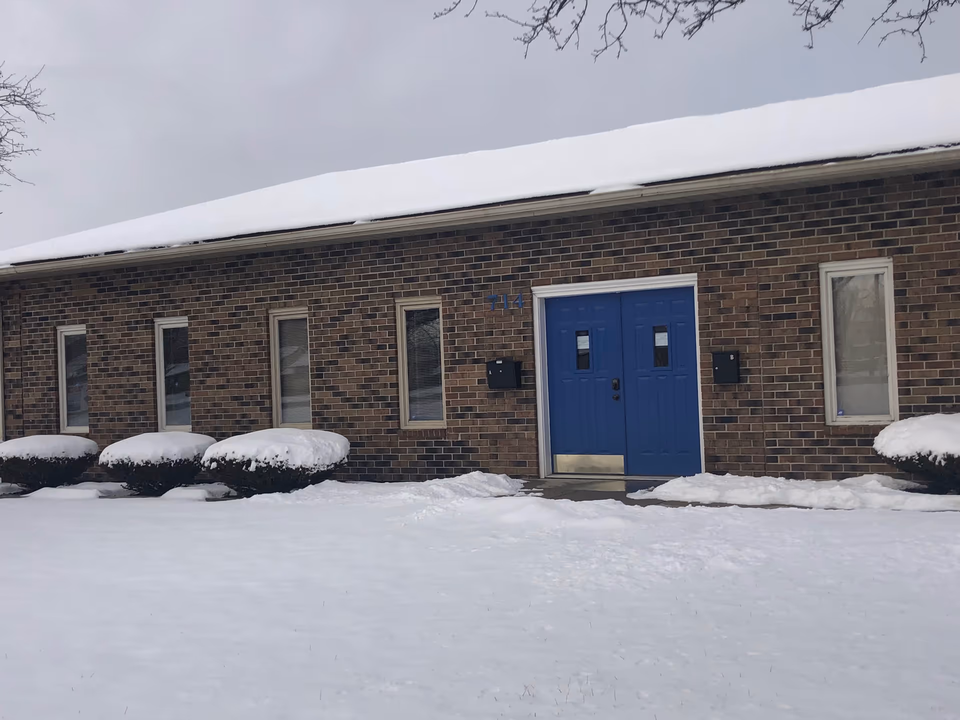 Brick facility exterior with blue double doors and snow-covered ground.