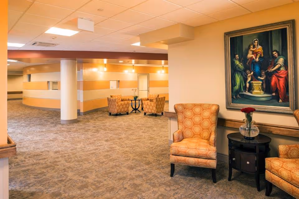 A spacious beige lobby with striped walls, seating, and a large framed painting.