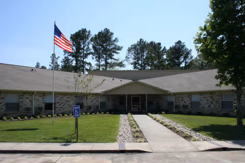 Exterior view of Hemphill Care Center with flag, walkway, and front lawn.