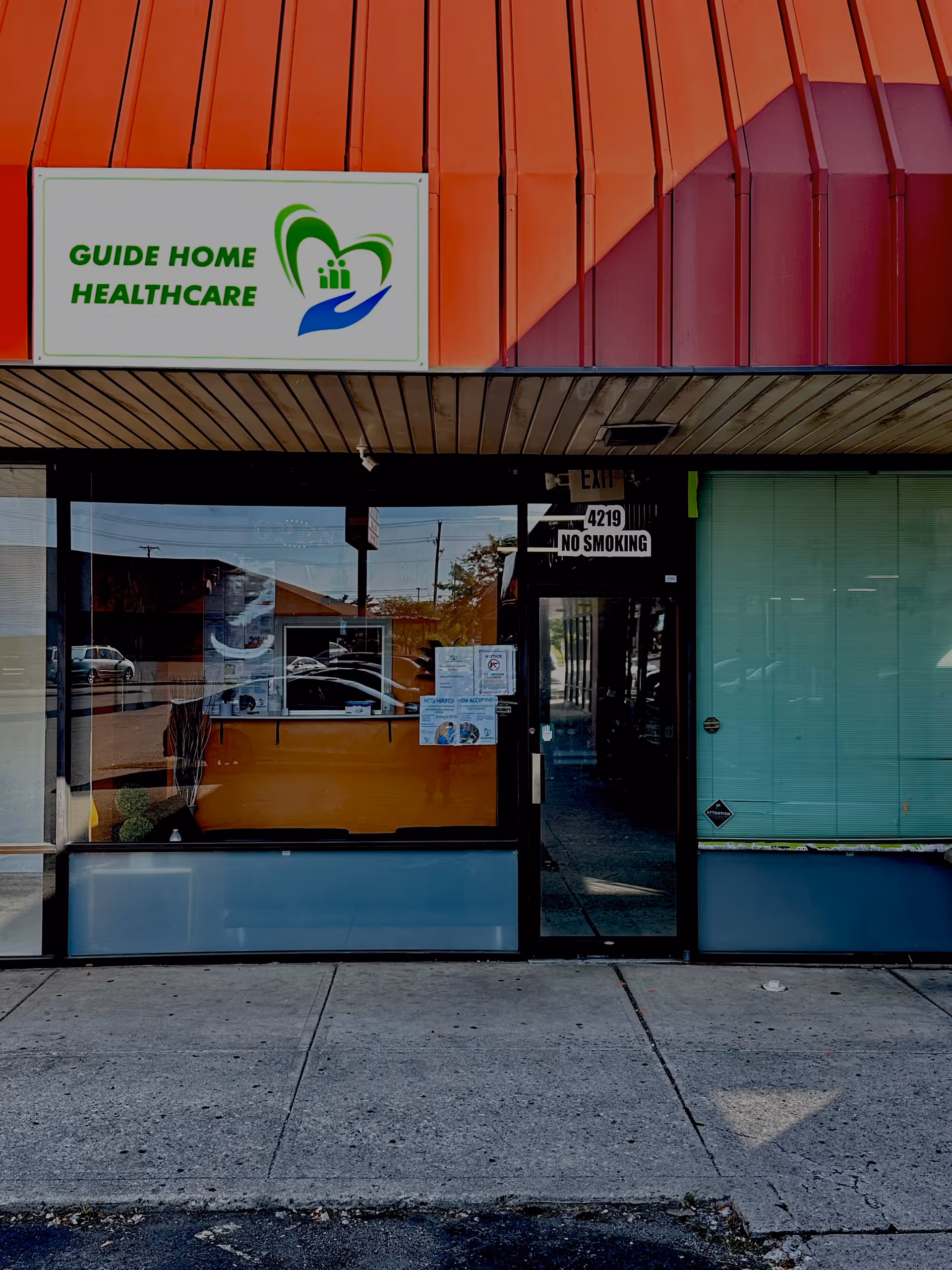 Exterior storefront with Guide Home Healthcare sign, glass doors, and orange awning
