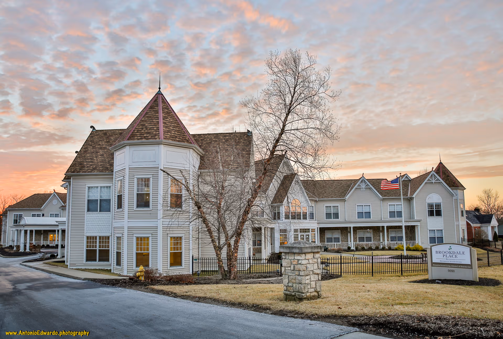 Exterior view of Brookdale Kenwood senior living facility with turreted building and flag