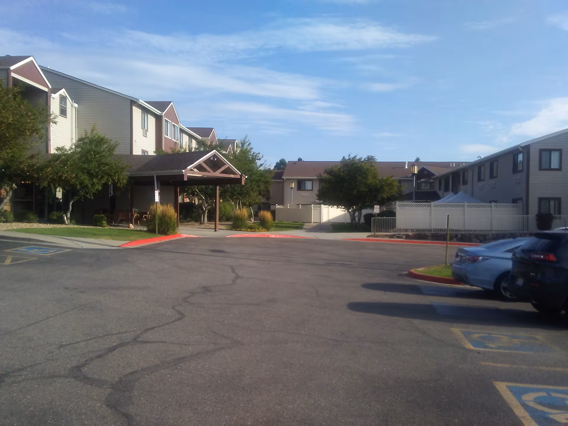 Exterior view of Northglenn Heights with a covered entrance and parked cars.
