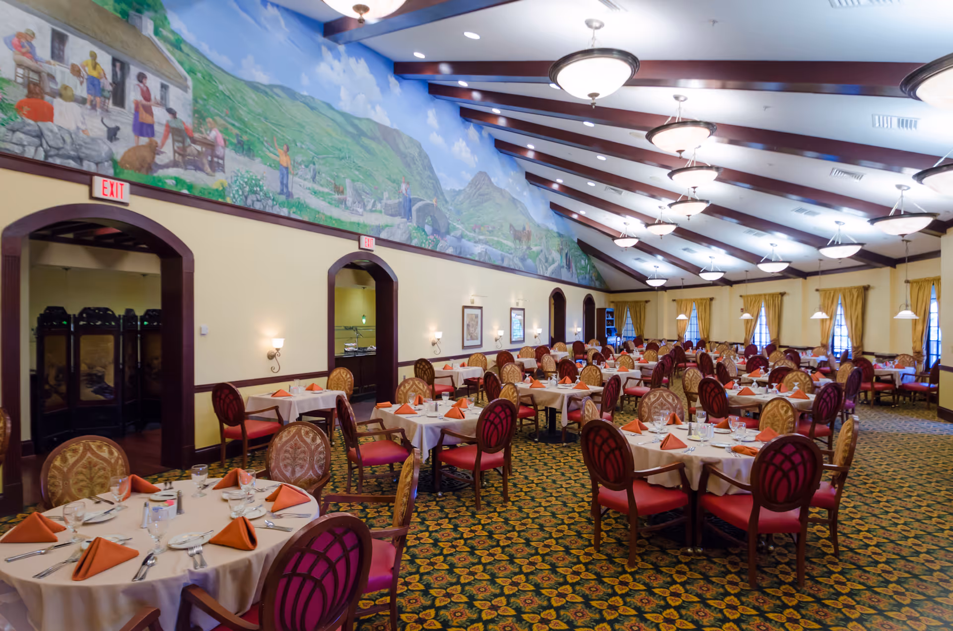 Spacious Maryfield Nursing Home dining hall with round tables, ornate chairs, and a mural wall.