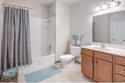 A clean bathroom featuring a bathtub with shower curtain, toilet, sink, mirror, and cabinets.