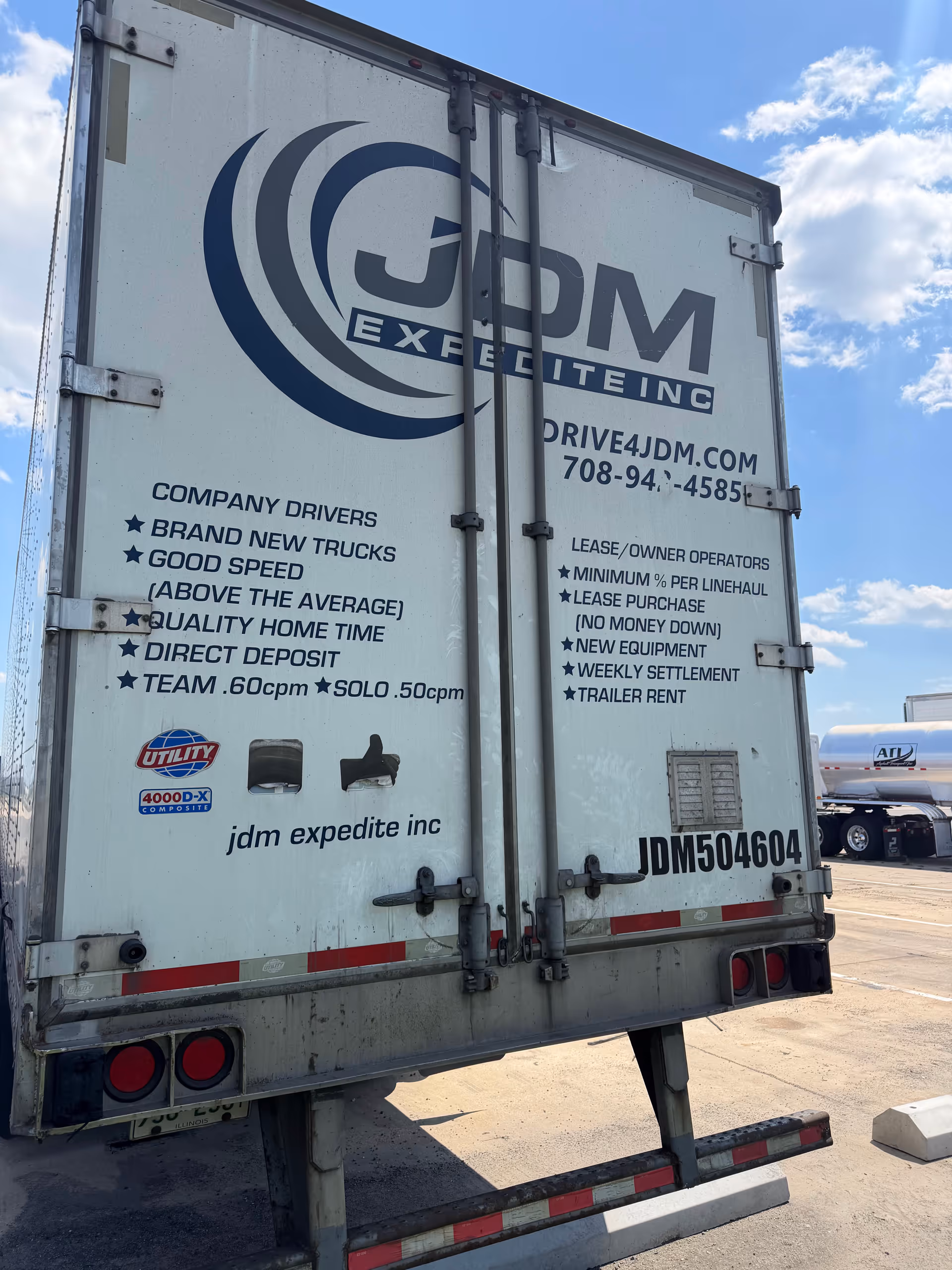 Rear view of a white delivery trailer with a large blue logo and text.