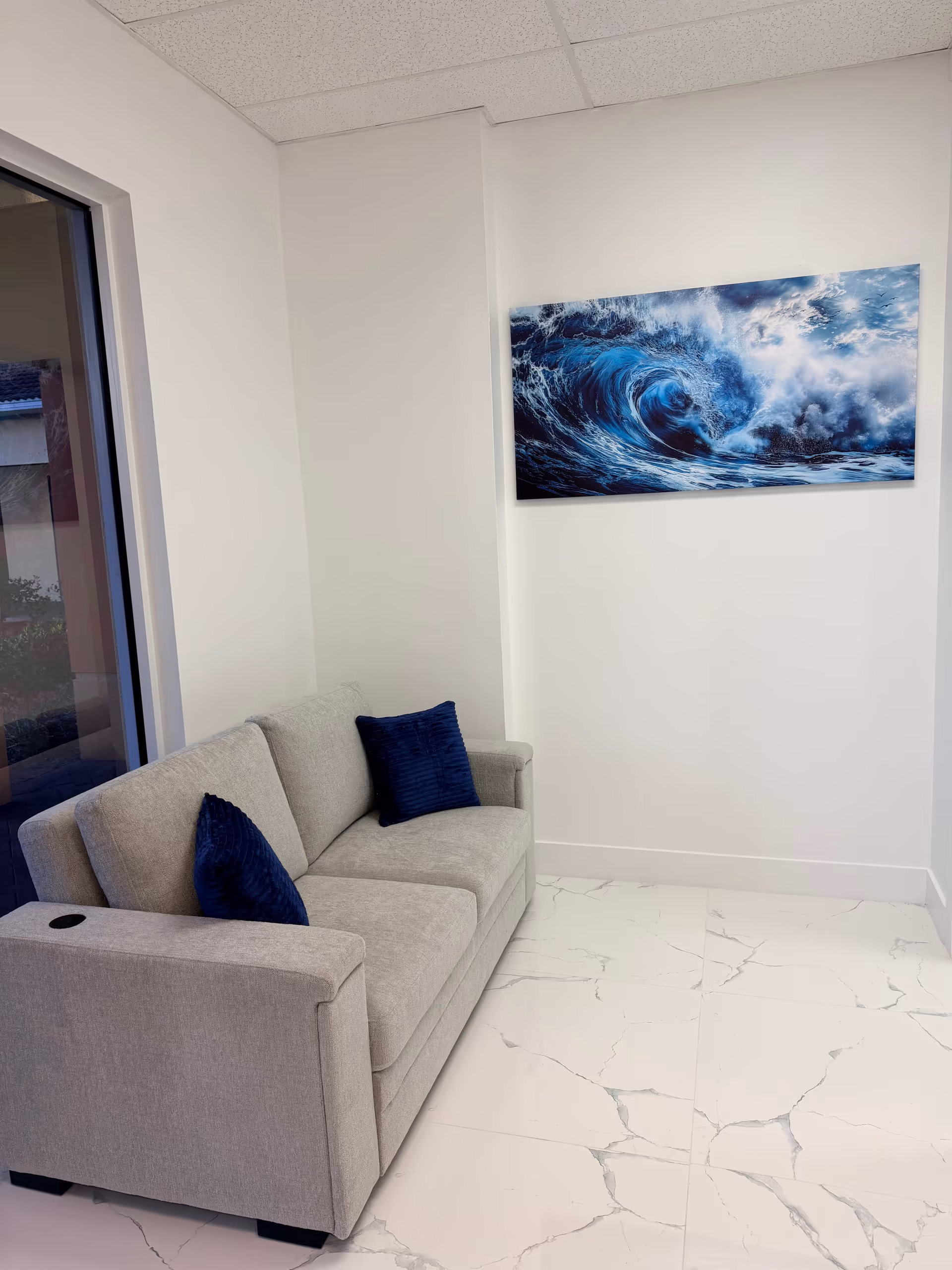Light-gray sofa with blue cushions in a bright lounge area.