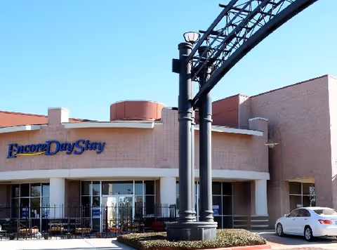 Exterior view of Encore Day Stay memory care building with entrance and parked car.