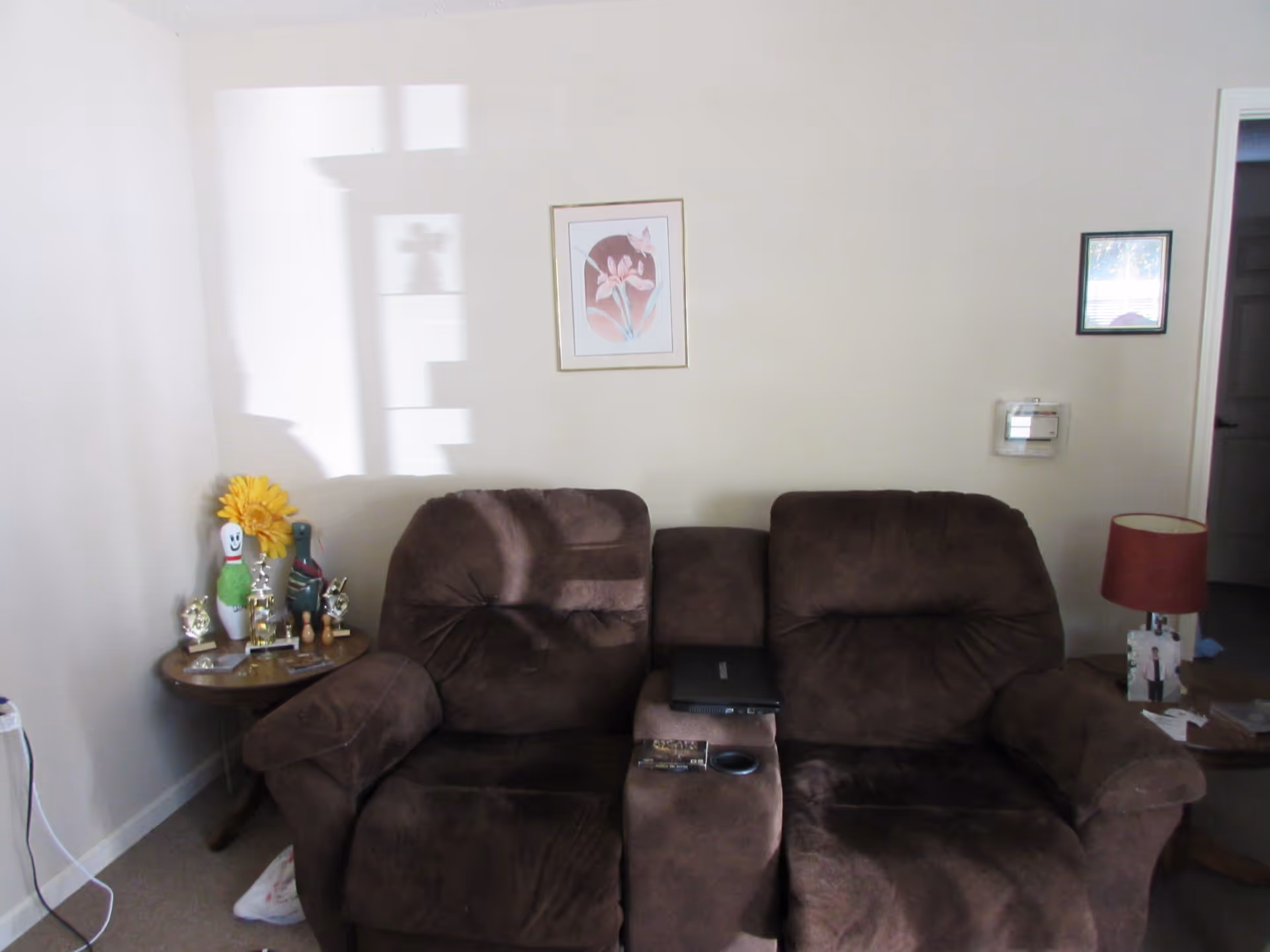 Brown living room sofa with laptop on center console, side tables, and wall art.