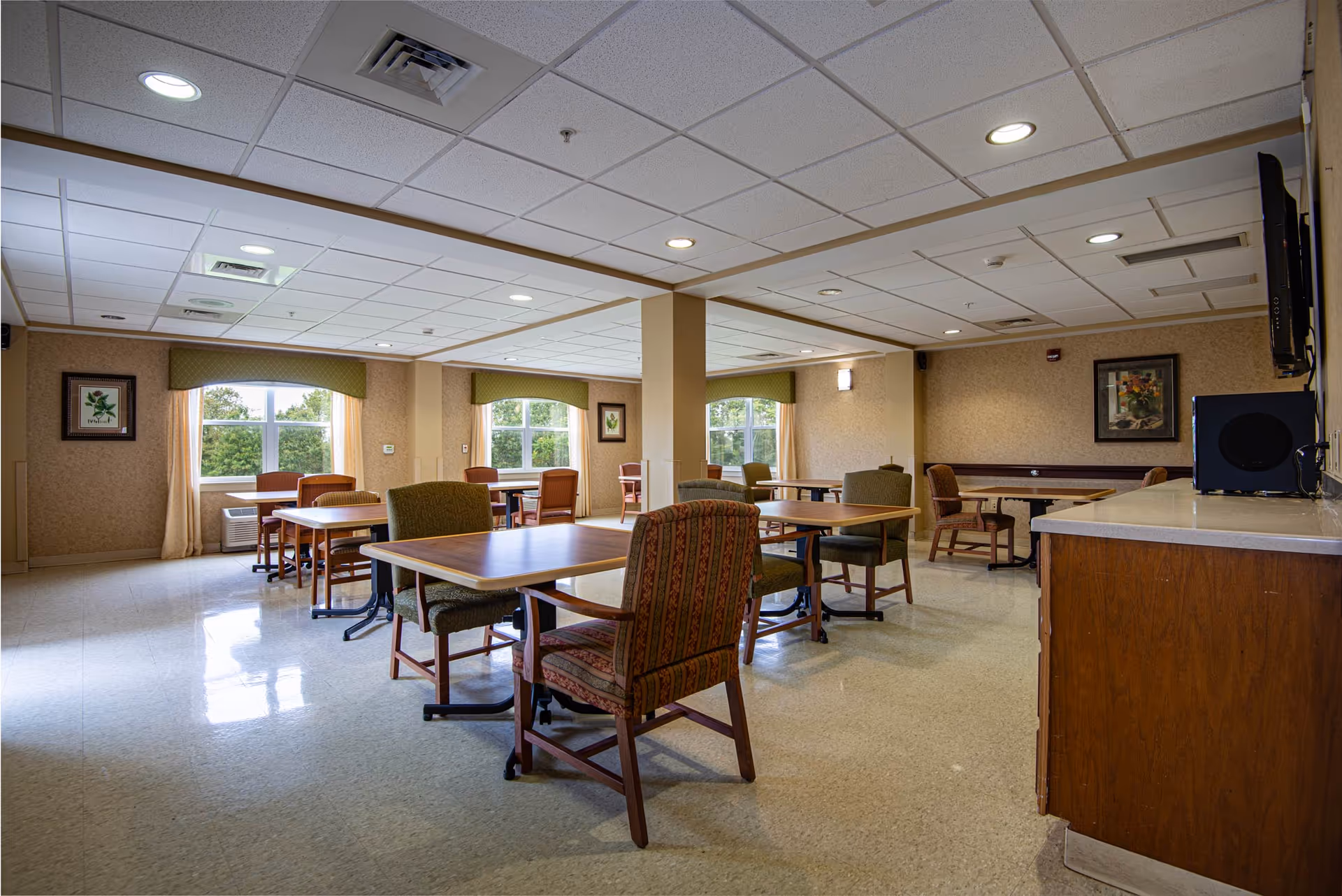 Senior living dining room with multiple tables, chairs, and windows