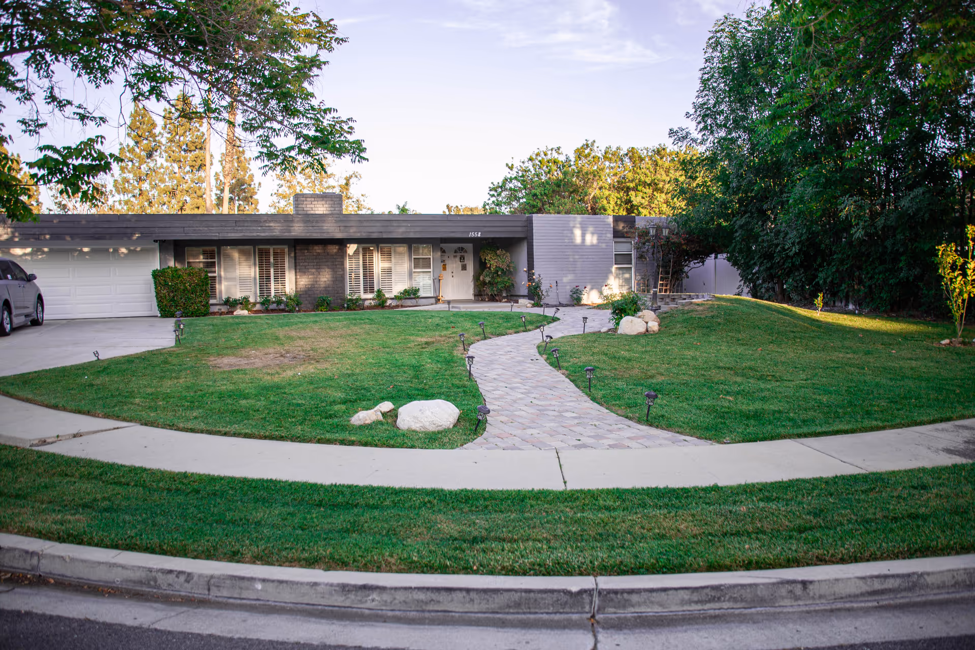 Exterior view of Sunshine Health Place with curved walkway, lawn, and trees.