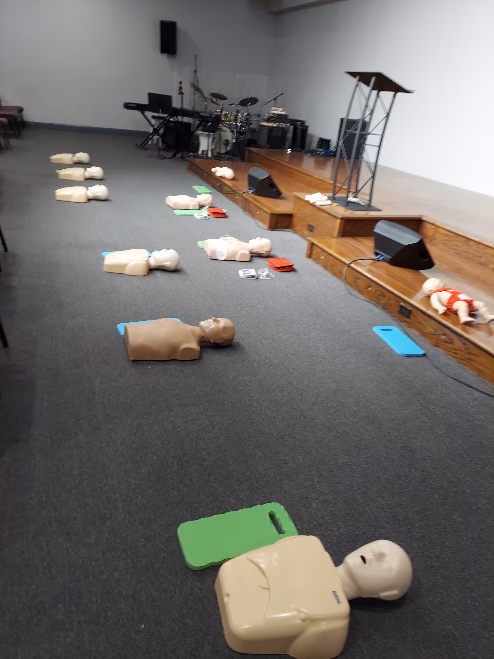 CPR training room with multiple mannequins and mats scattered on the floor.