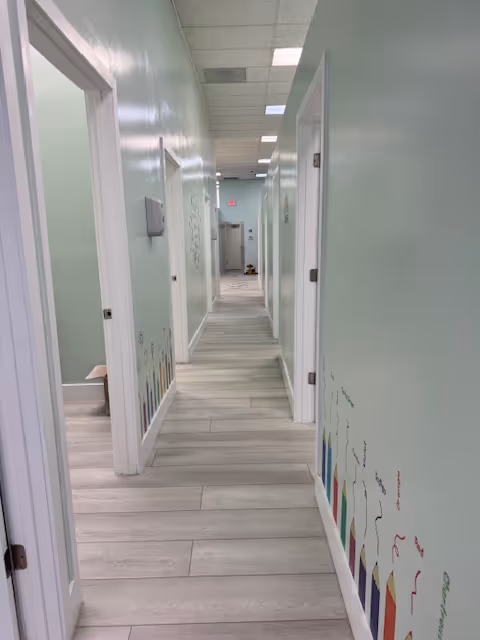 A long pastel-green interior hallway with several doors and a tiled floor.