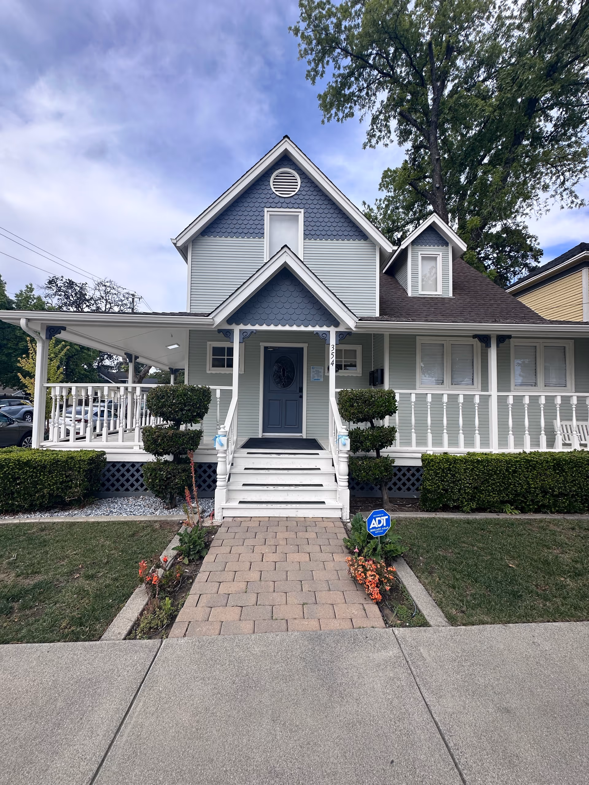 Blue gray, two story senior care house with a central front entrance and wide porch.