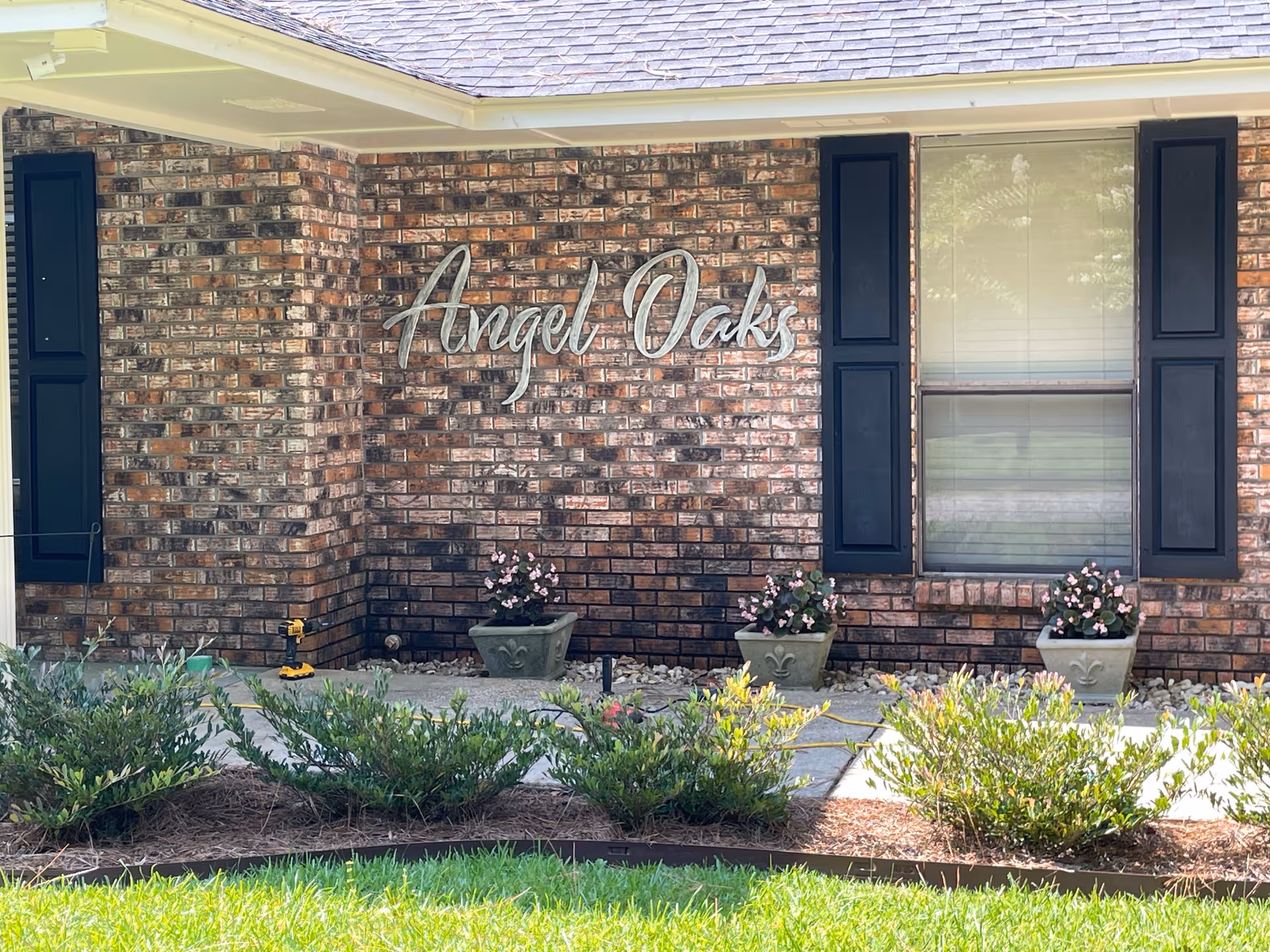 Brick exterior of Angel Oaks facility with window, shutters, and flower planters.