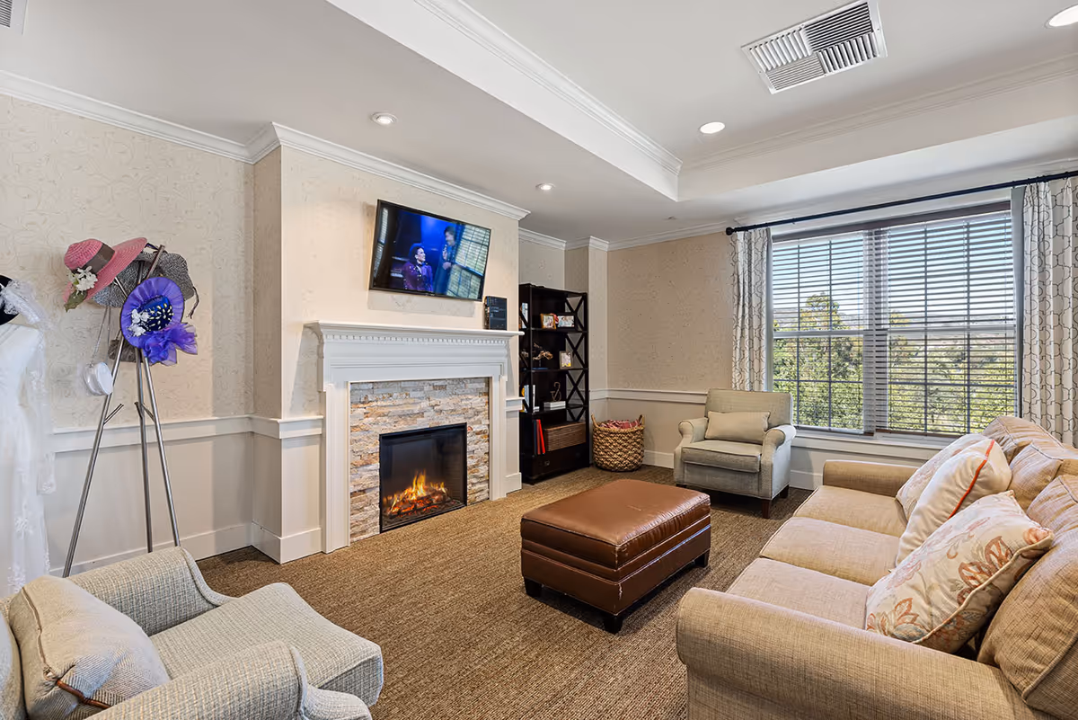 Cozy lounge with fireplace, seating, TV, and large windows in a living room.