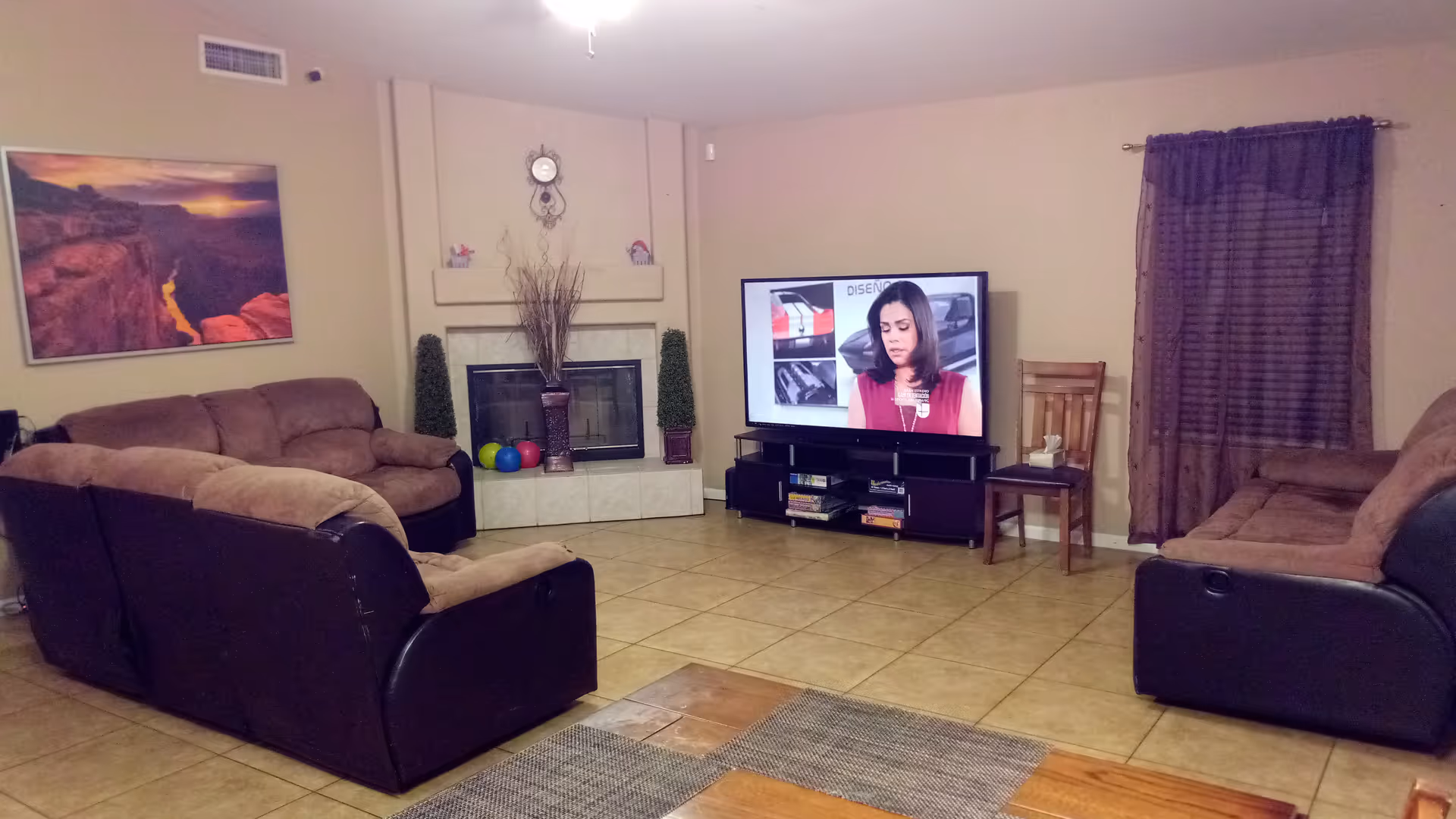 Cozy living room with tan sectional sofas, fireplace, TV, and tiled floor.