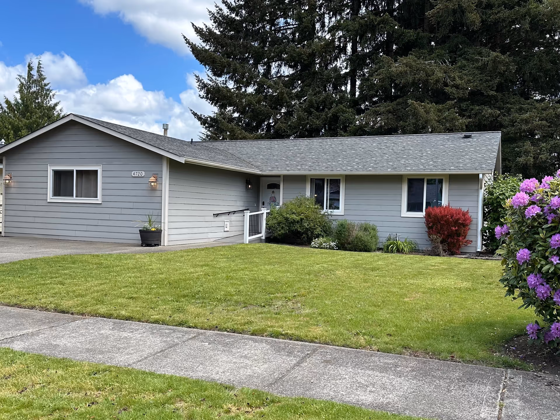 Front exterior view of a single-story gray siding home with a manicured lawn.