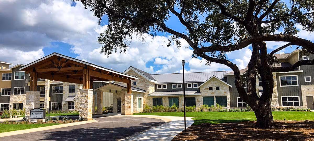 Exterior view of The Delaney at Georgetown Village with a stone entrance canopy and tree