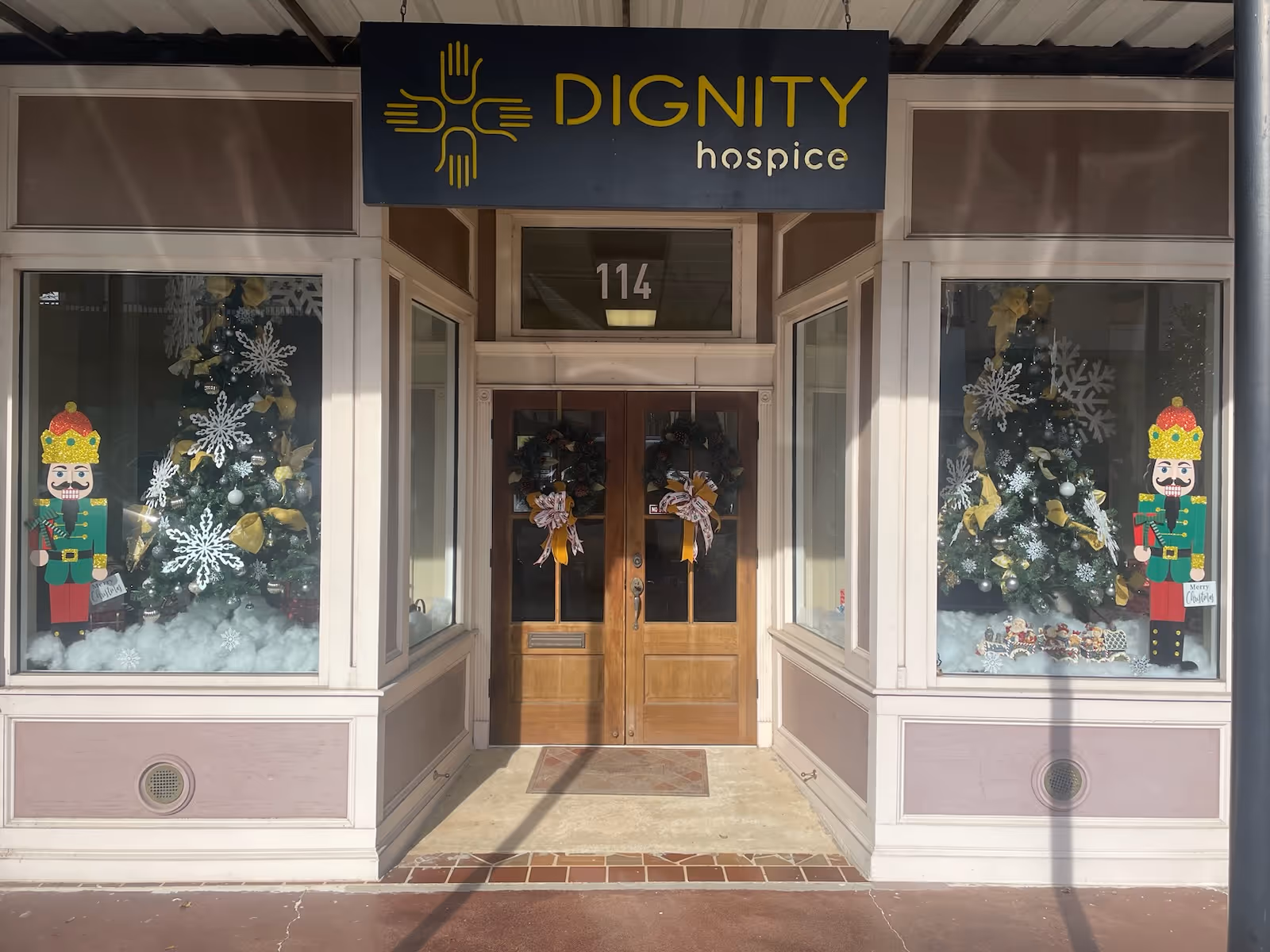 Entrance of DIGNITY hospice with holiday decorations and double wooden doors.