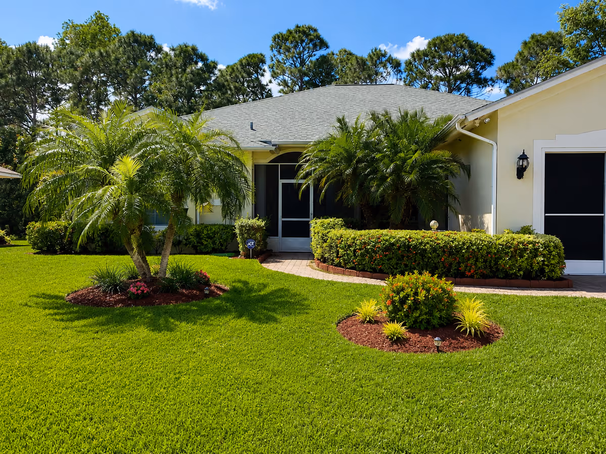 Front view of a single-story senior care facility with palm trees and landscaped lawn.