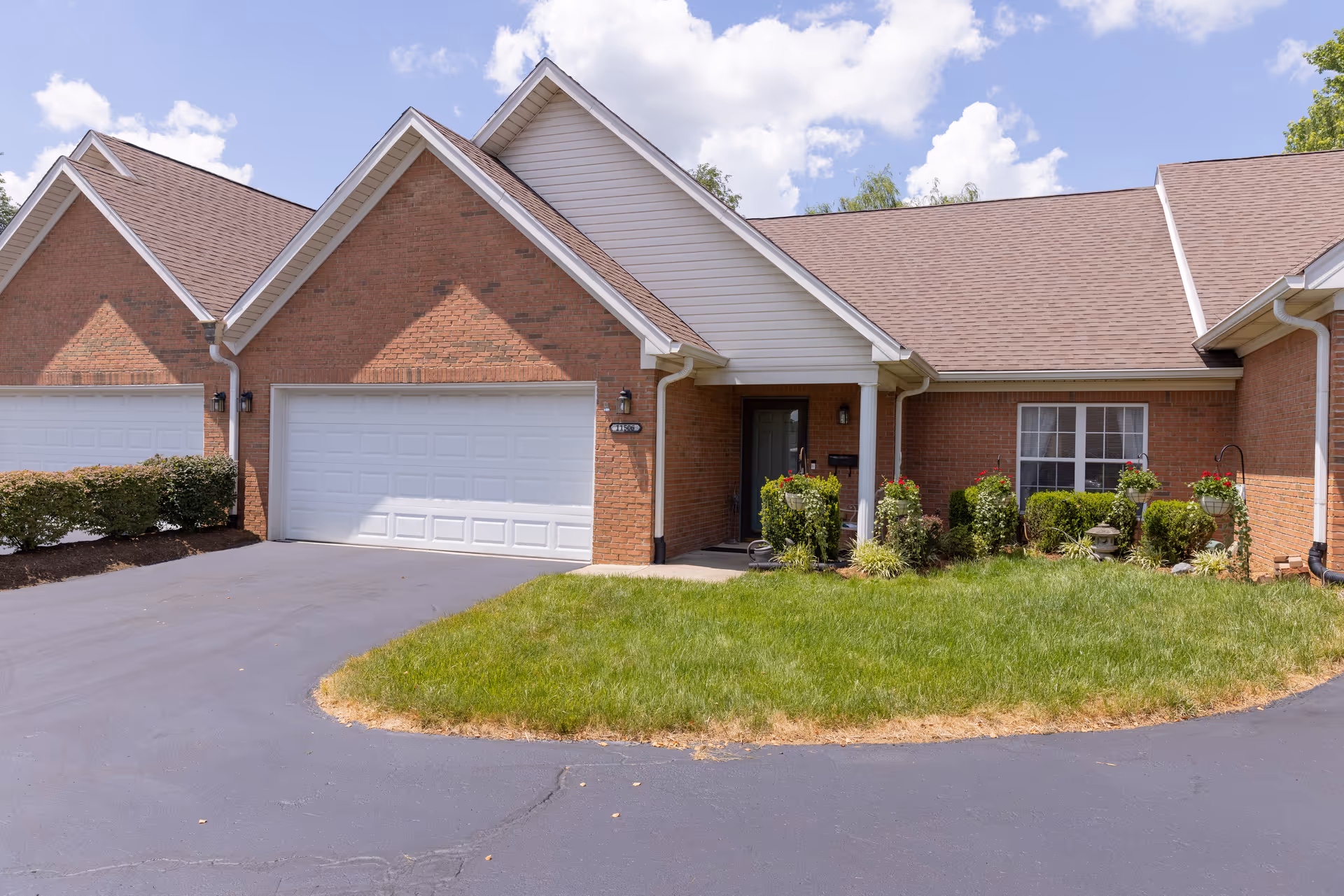 Front view of a brick senior living facility with a two-car garage and landscaping.