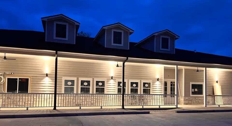 Exterior view of a single-story care facility at dusk with a covered front entrance.