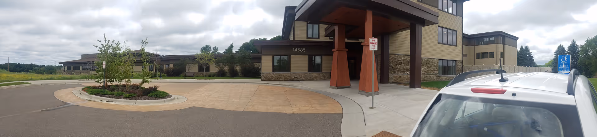 Exterior view of The Birches at Trillium Woods entrance with canopy and parking.