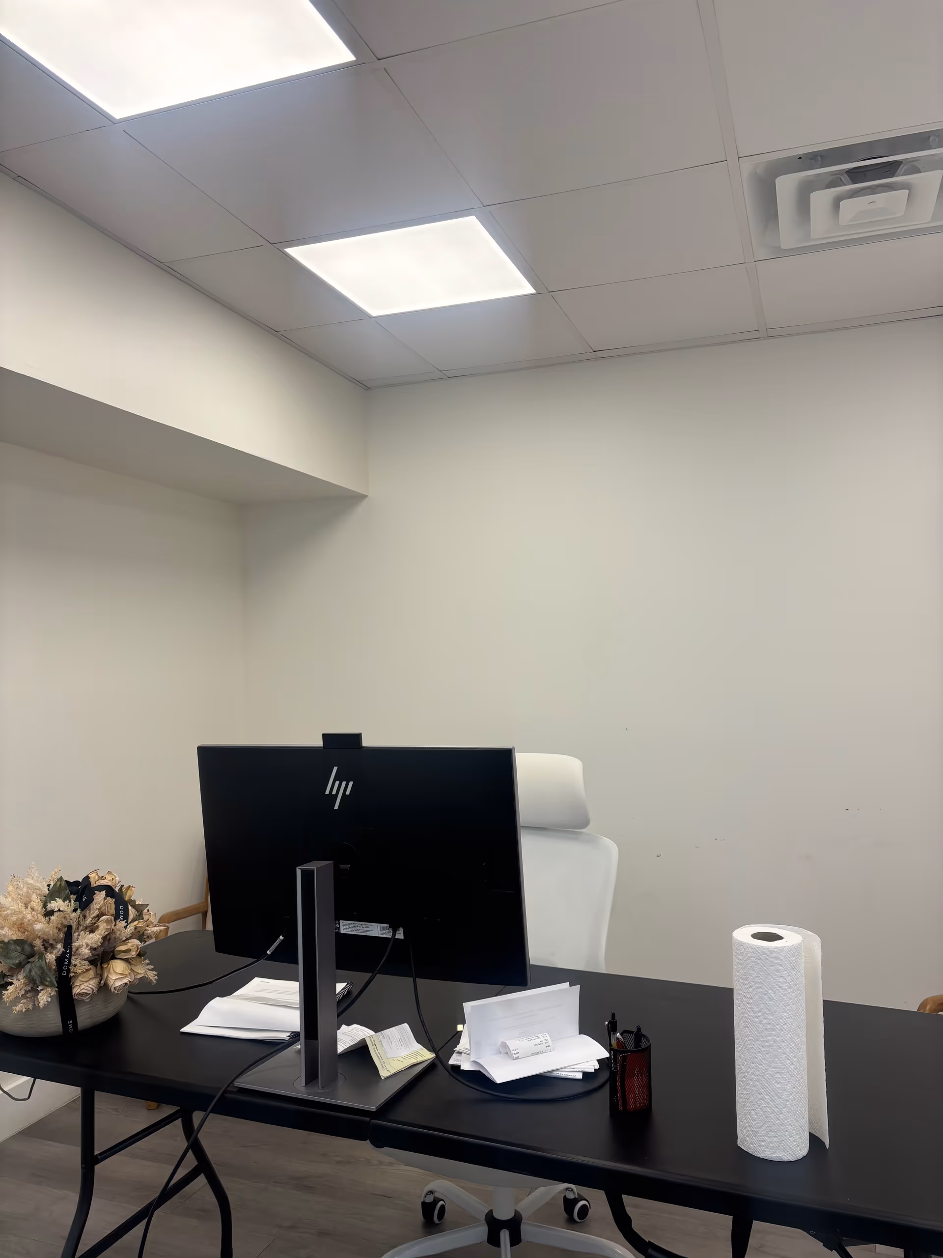 Modern office desk with computer monitor, papers, and a white chair.