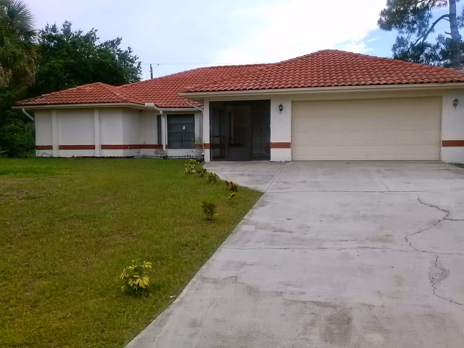 Front exterior of a single-story home with a red-tiled roof and two-car garage.