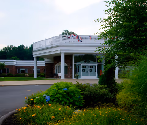Front entrance of Linda Manor Extended Care Facility with brick walls, columns, and landscaped grounds.