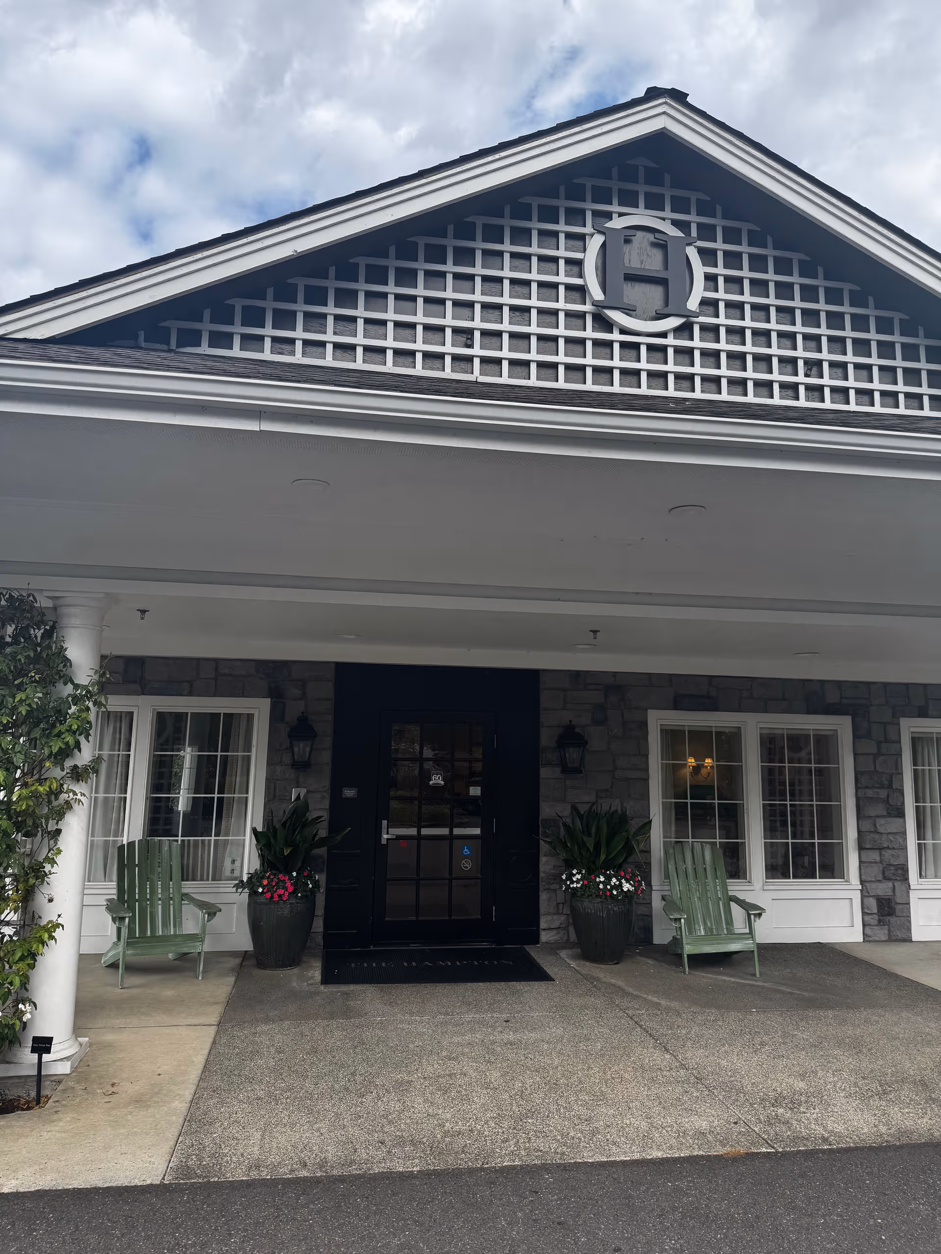 Front entrance of The Hampton and Ashley Inn Memory Care Community with stone facade and planters.