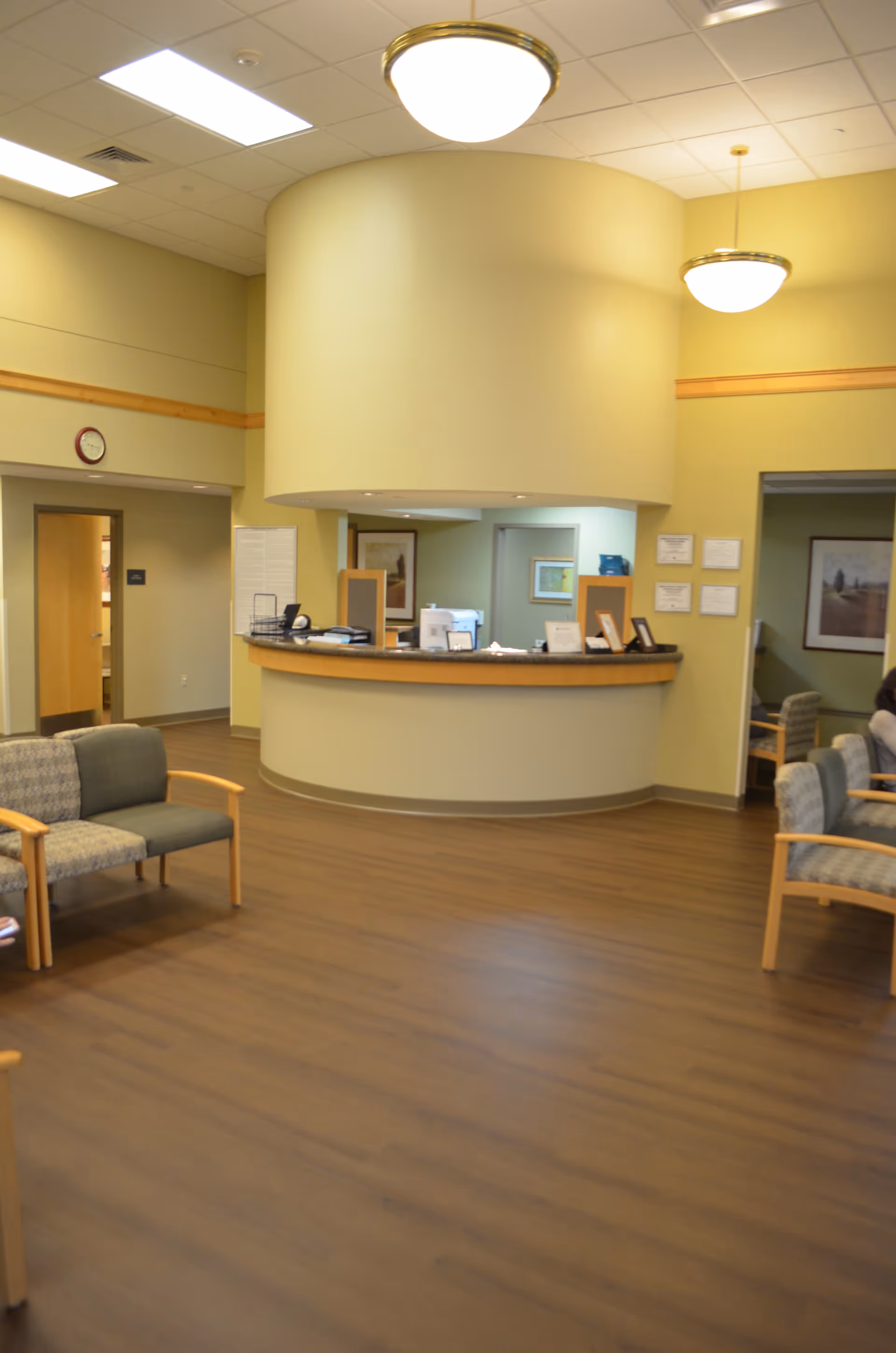 Reception desk in a spacious, well-lit senior living lobby with seating.