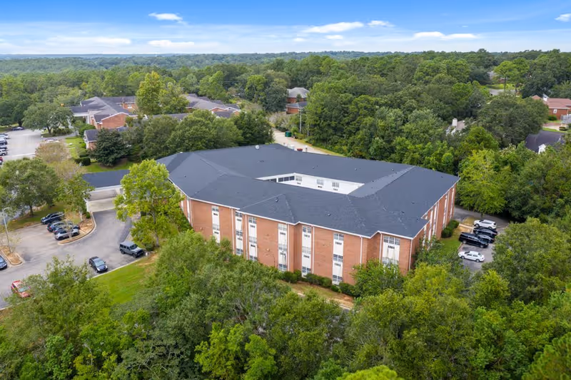 Aerial view of Knollwood Healthcare Center exterior, brick building amid trees with parking.