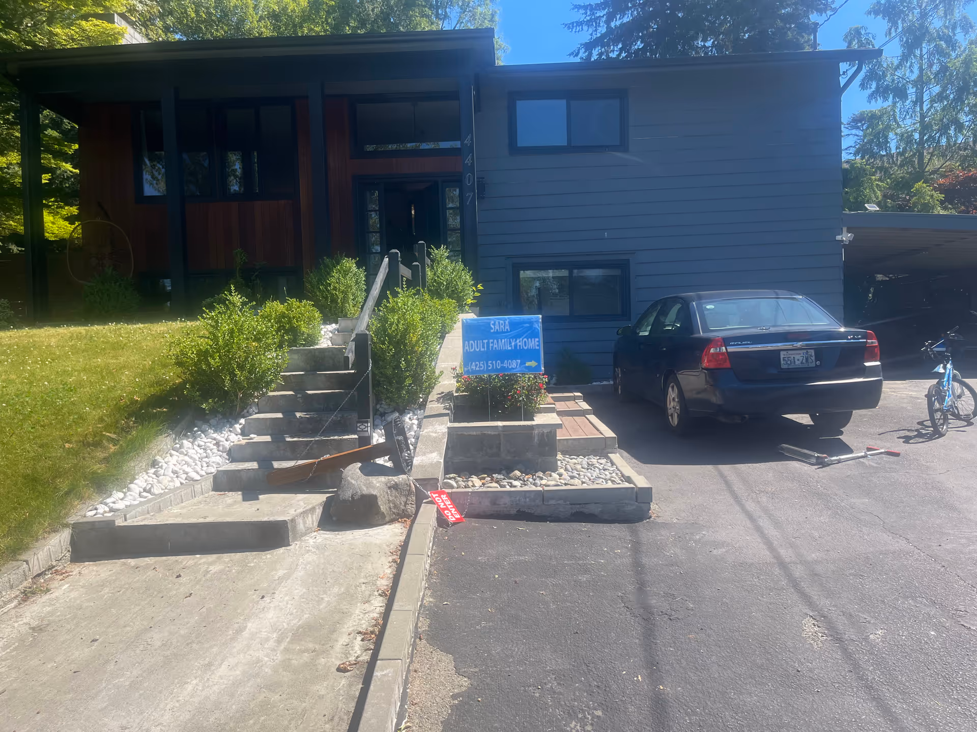 Front exterior view of Sara Adult Family Home with stairs, sign, and a parked car.